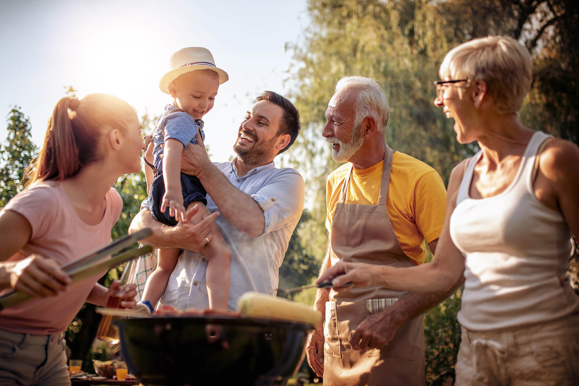 Family gathered around a BBQ grill, enjoying outdoor cooking together